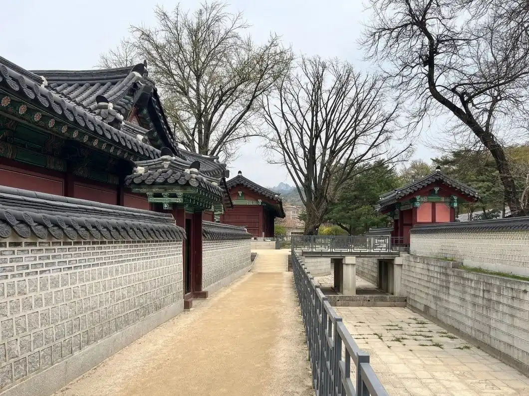 A palace walkway between stone walls and old trees