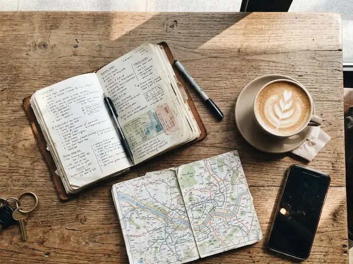 A travel notebook, a map, a phone and a latte on a café table in Seoul