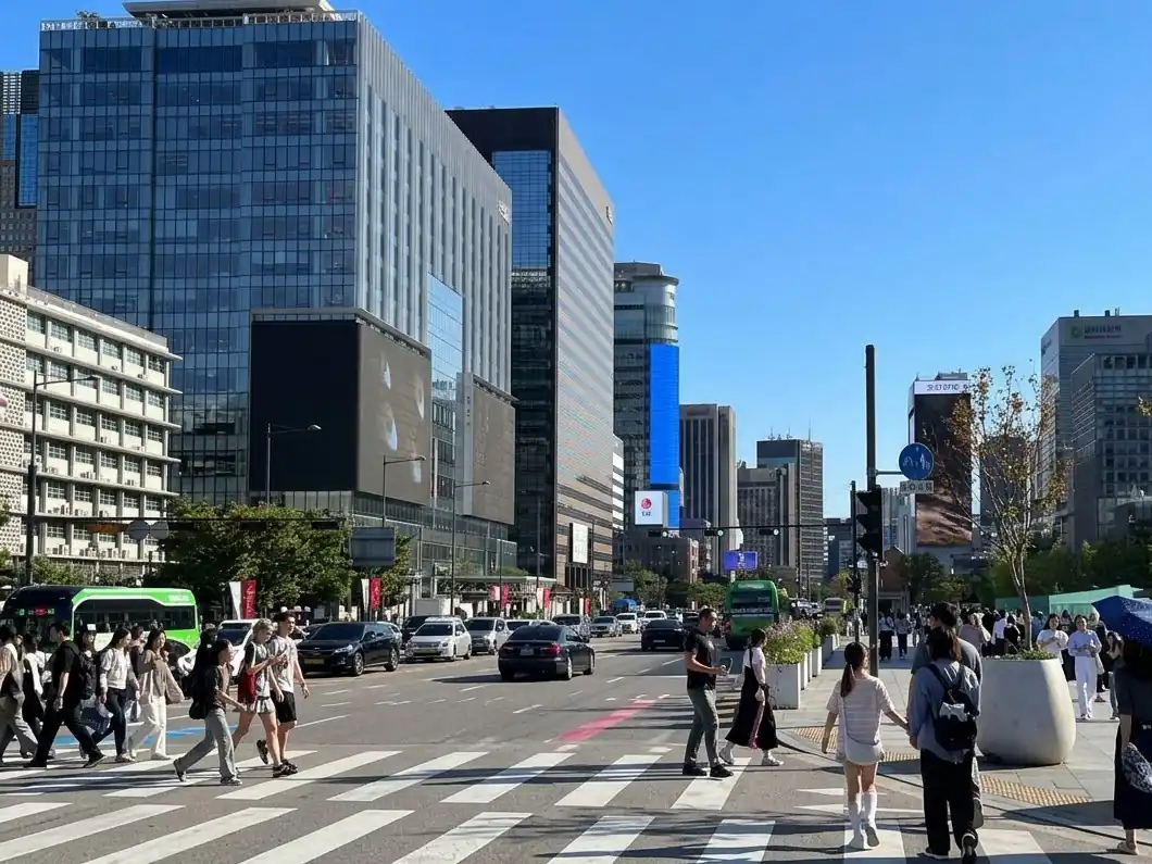 Pedestrians crossing a wide street between Seoul skyscrapers