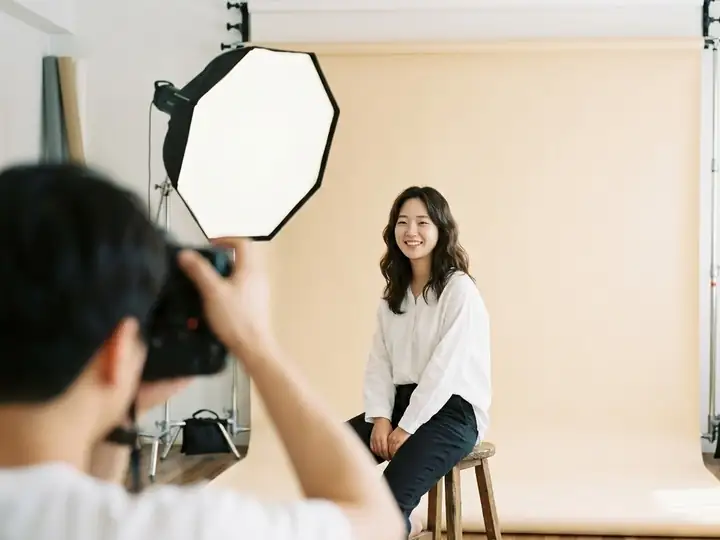 A Korean woman posing on a stool against a beige backdrop in a Seoul photo studio